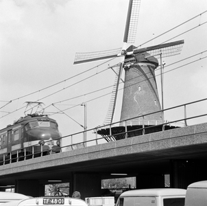 857532 Gezicht op de molen De Roos aan de Phoenixstraat te Delft, met op de voorgrond een electrisch treinstel mat. ...